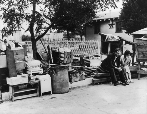 TGD - Depressed An evicted couple sitting on the curb surrounded by their belongings in Los Angeles, California - Getty